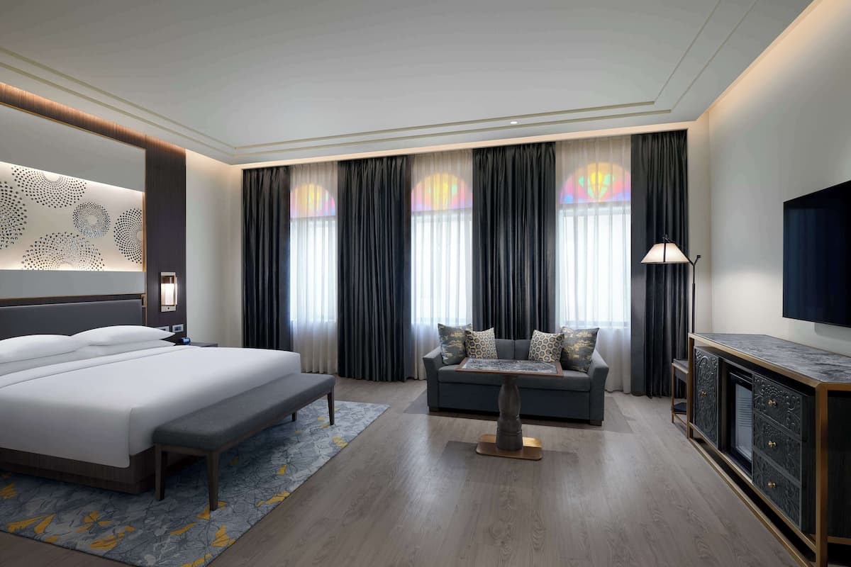 Une chambre d’hôtel moderne avec un grand lit, un canapé, une petite table et un téléviseur.