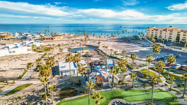 A resort with a pool area, palm trees, and a view of the ocean. - Hotel Casa Blanca Golf Villas (Puerto Peñasco)