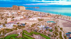 An aerial view of a coastal resort with multiple buildings, a beach, and a golf course. - Hotel Casa Blanca Golf Villas (Puerto Peñasco)