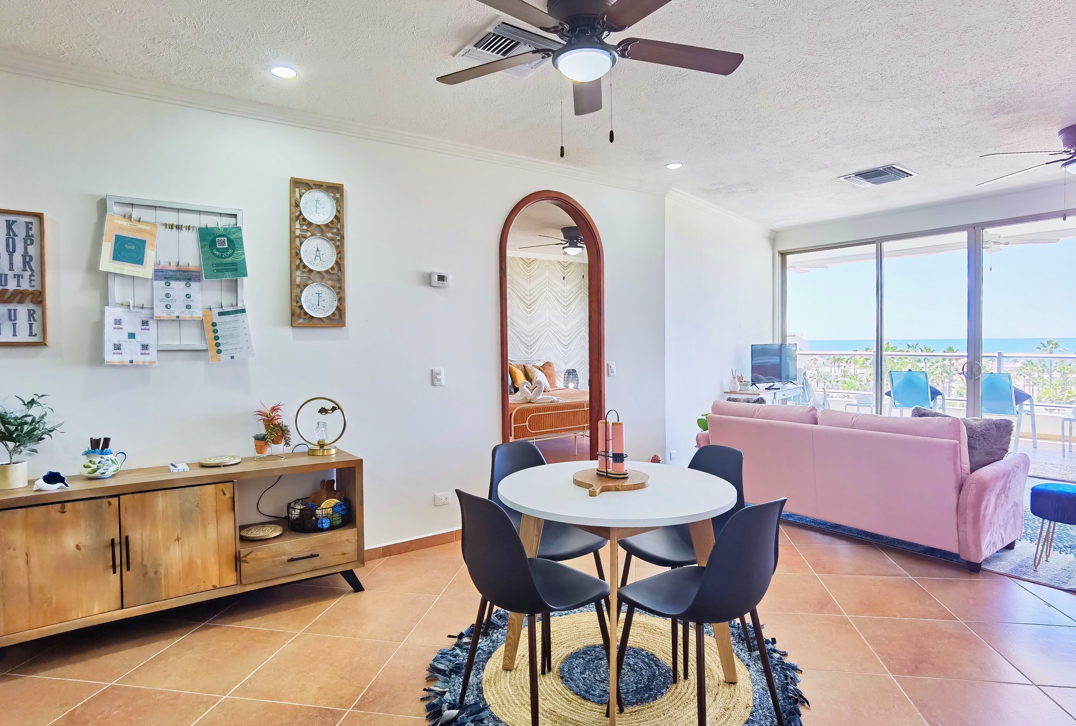 A modern living room with a round table, black chairs, a wooden cabinet, and a large mirror.