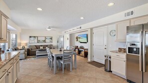 A spacious kitchen with a dining area, white cabinetry, and a stainless steel refrigerator. - Steps to Sand, Pet-Friendly Oceanfront w. Dog Run (Ponte Vedra Beach)
