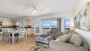 A spacious living area with a balcony, a dining table, and a sofa. - Shore Beats Work Home, Deck & Oceanfront Views (Ponte Vedra Beach)