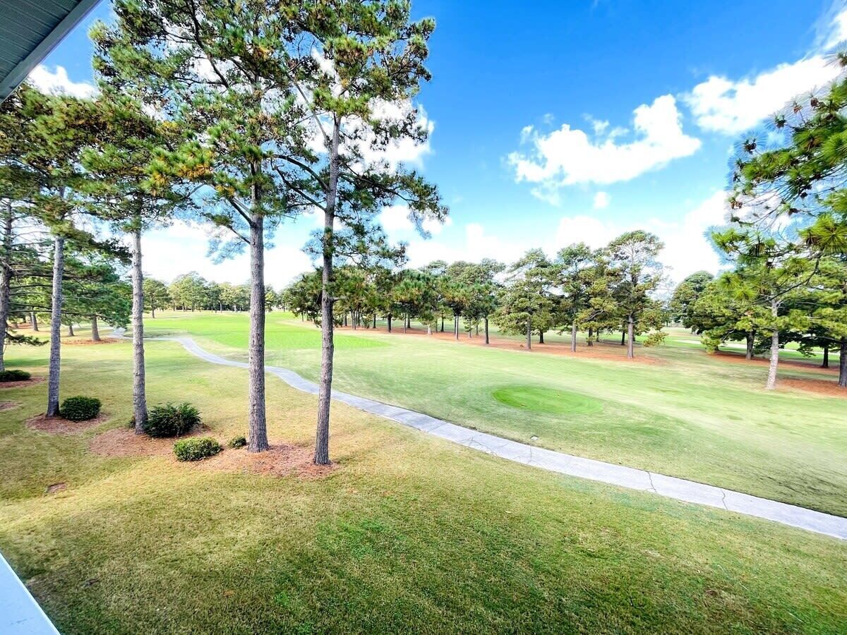 A golf course with a clear path, surrounded by evenly spaced trees and well-maintained grass.