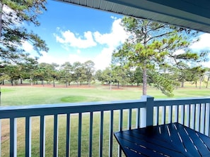 A covered outdoor area with a view of a golf course.