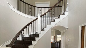 Una imponente escalera con peldaños de madera oscura y barandales blancos, que conduce a un piso superior.