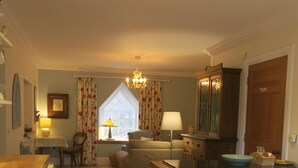 A cozy kitchen with a wooden table, a washing machine, and a dining area with a table and chairs. - Castle Annex in Trossachs National Park (Aberfoyle)