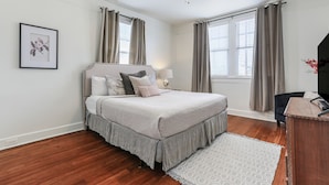 Une chambre à coucher avec un lit, un ventilateur de plafond, un bureau et une chaise.