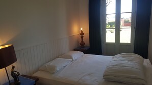 Een hotelkamer met een bed, nachtkastje, lamp en raam met gordijnen.