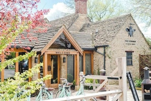 A traditional stone building with a welcoming sign, a wooden entrance, and a chimney.
