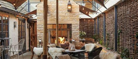 An outdoor seating area with wicker furniture and a stone wall backdrop.