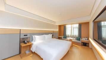 A modern hotel room with a large bed, bedside tables, a nightstand, a window with curtains, and a view of the outdoors.