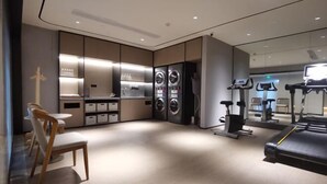 A modern gym with exercise equipment, a seating area, and a large mirror.