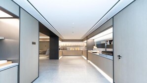 A modern hotel corridor with a neutral color palette, a reception area, and a view into the dining area.