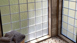 A room with a large sliding glass door, a wooden bench with a towel, and a pebble-patterned floor.