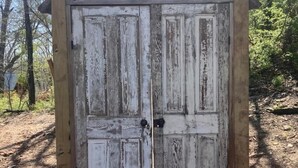 A rustic wooden structure with a weathered door and a small wooden ramp leading up to it.