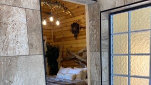 A cozy room with a bed, a wooden dresser, and a stone wall.