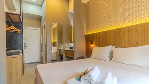 A hotel room with a large bed, a wooden wardrobe, a mirror, and a bathroom visible through an open door. - Studios E-side Vila Madalena (São Paulo)