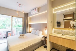 Habitación de hotel con una cama grande, un baño con espejo y vistas al exterior.