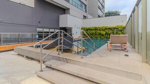 A rooftop pool area with steps leading to the pool, a bench, and a hedge. - Studios E-side Vila Madalena (São Paulo)