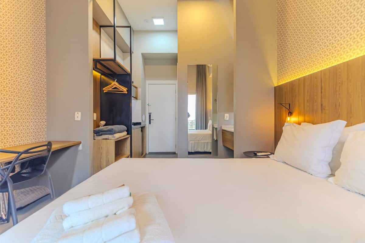 Ein Hotelzimmer mit Bett, Schreibtisch, Stuhl, Kleiderschrank und Spiegel.