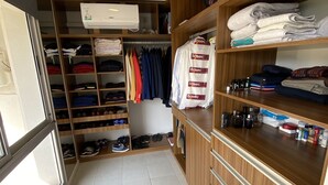 A walk-in closet with shelves for folded clothes, a shoe rack, and a bench. - Donna Alda Tower incredible views (Salta)