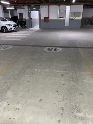 A parking garage with marked parking spaces, a white car, and a motorcycle.