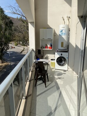 A balcony with a table and chairs, a washing machine, and a water heater. - Donna Alda Tower: Incredible Views (Salta)