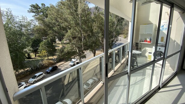 A balcony with a view of a street, parked cars, and trees. - Donna Alda Tower incredible views (Salta)
