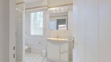A bathroom with a toilet, sink, and shower area.