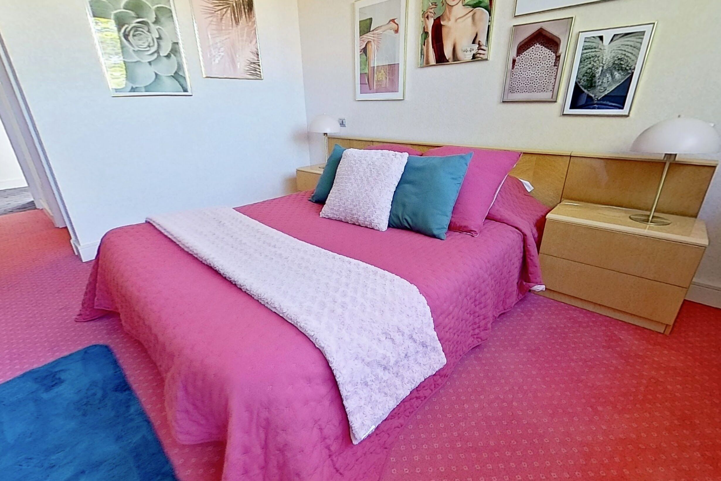 Une chambre à coucher avec un lit, une table de chevet et un mur orné de tableaux encadrés.