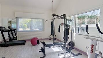 Een sportschool met trainingsapparatuur, een loopband en een groot raam.