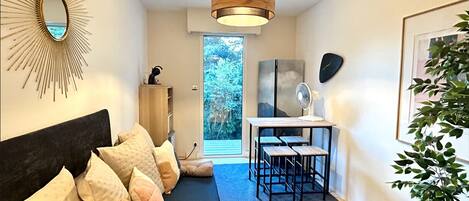 A modern bedroom with a bed, a desk, and a view of the outdoors.