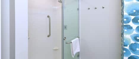A glass-enclosed shower with a white towel hanging on the door handle.