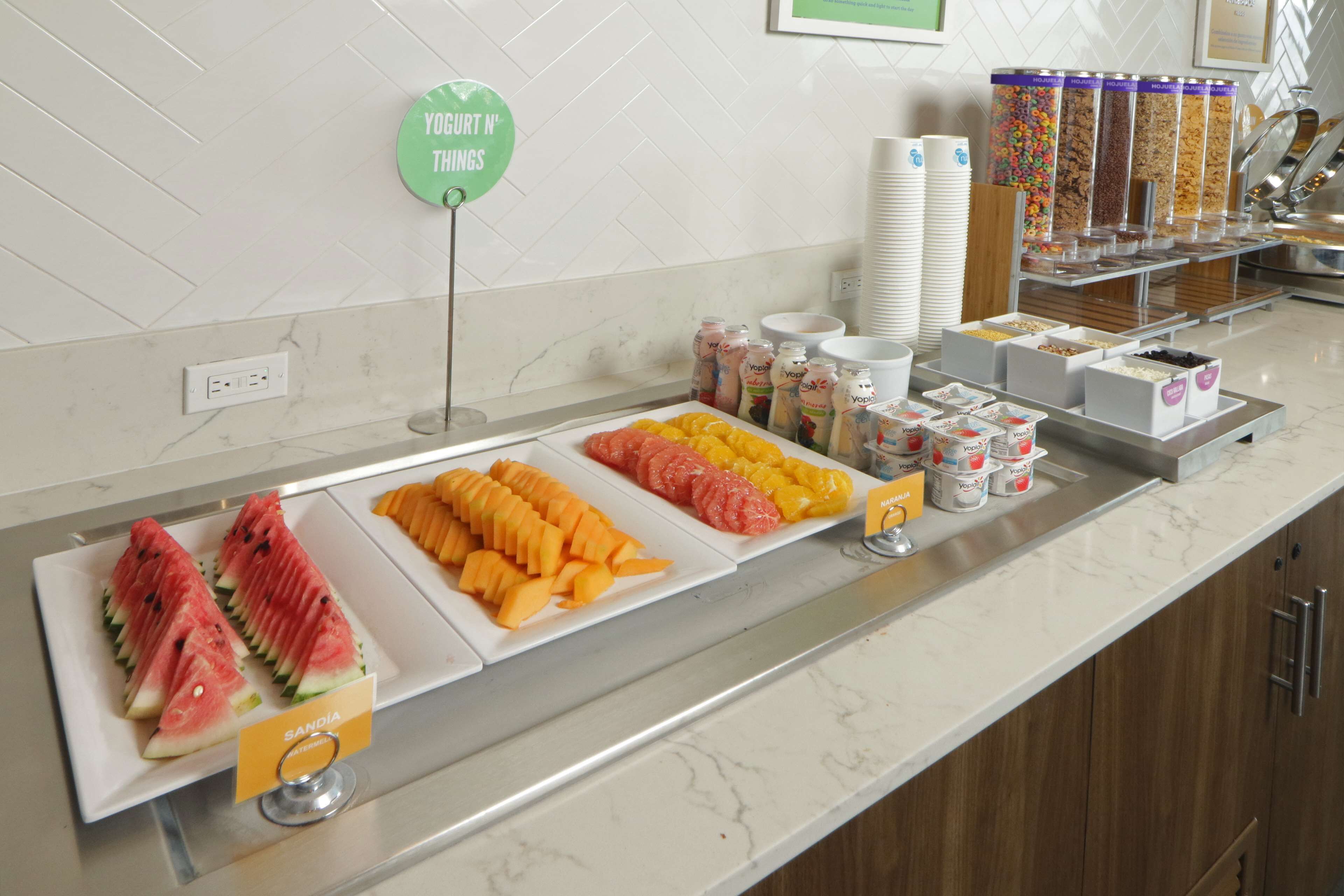 A buffet with various fruits and yogurt containers.