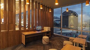 A modern office space with a large window, wooden paneling, and a desk with a computer. - Tru By Hilton Monterrey Fundidora (Monterrey)