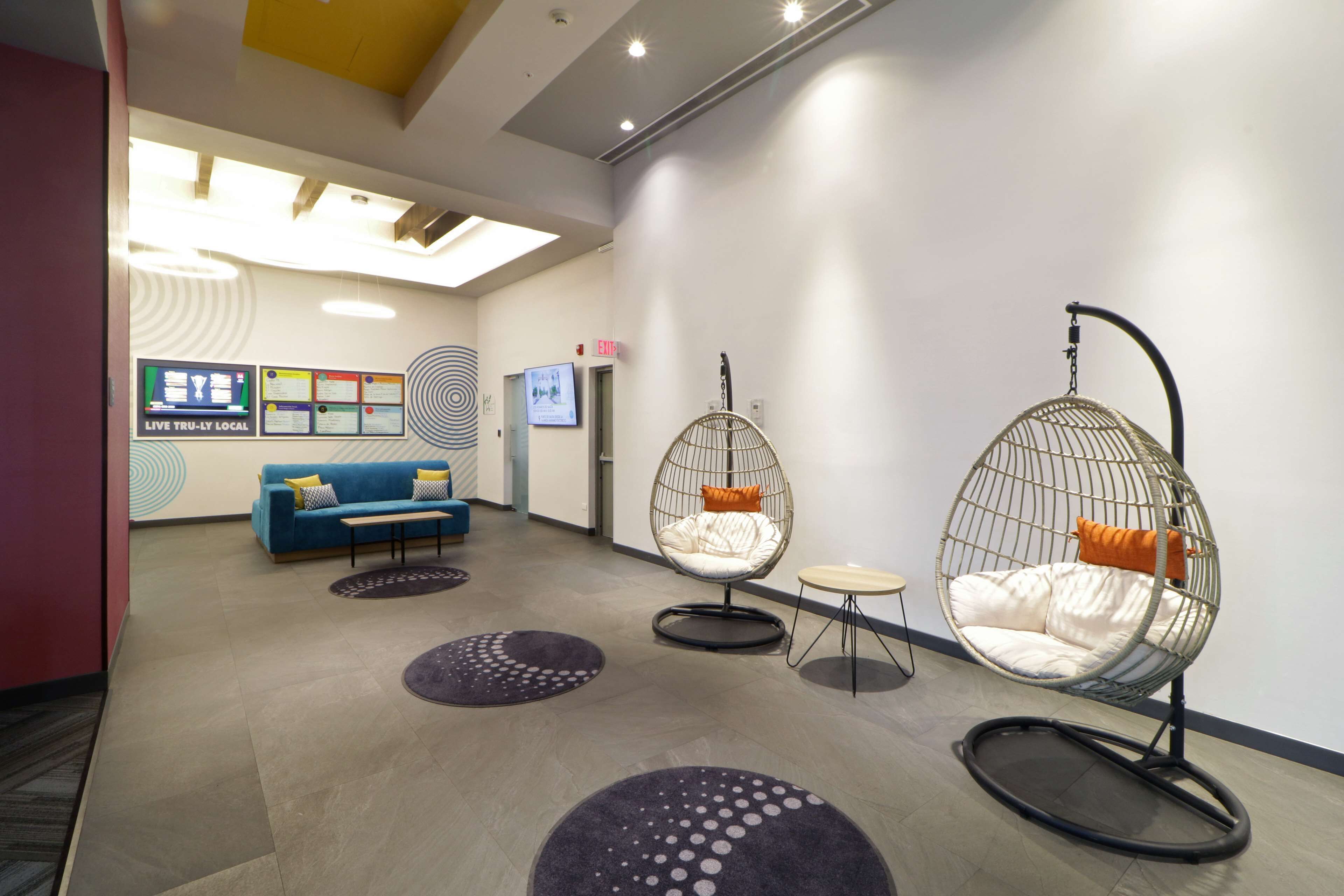 A modern lobby with a blue sofa, two egg-shaped chairs, and a small table.