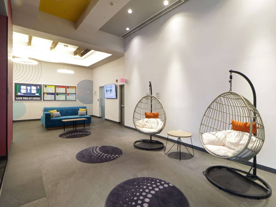 Un hall d’entrée moderne avec un canapé bleu, deux fauteuils en forme d’œuf et une petite table.