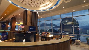 A hotel reception area with a modern design, featuring a large window with a view of mountains and a bridge, a reception desk, and a seating area with a view. - Tru By Hilton Monterrey Fundidora (Monterrey)