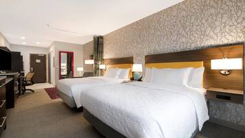 A hotel room with two beds, a desk, a chair, and a television.