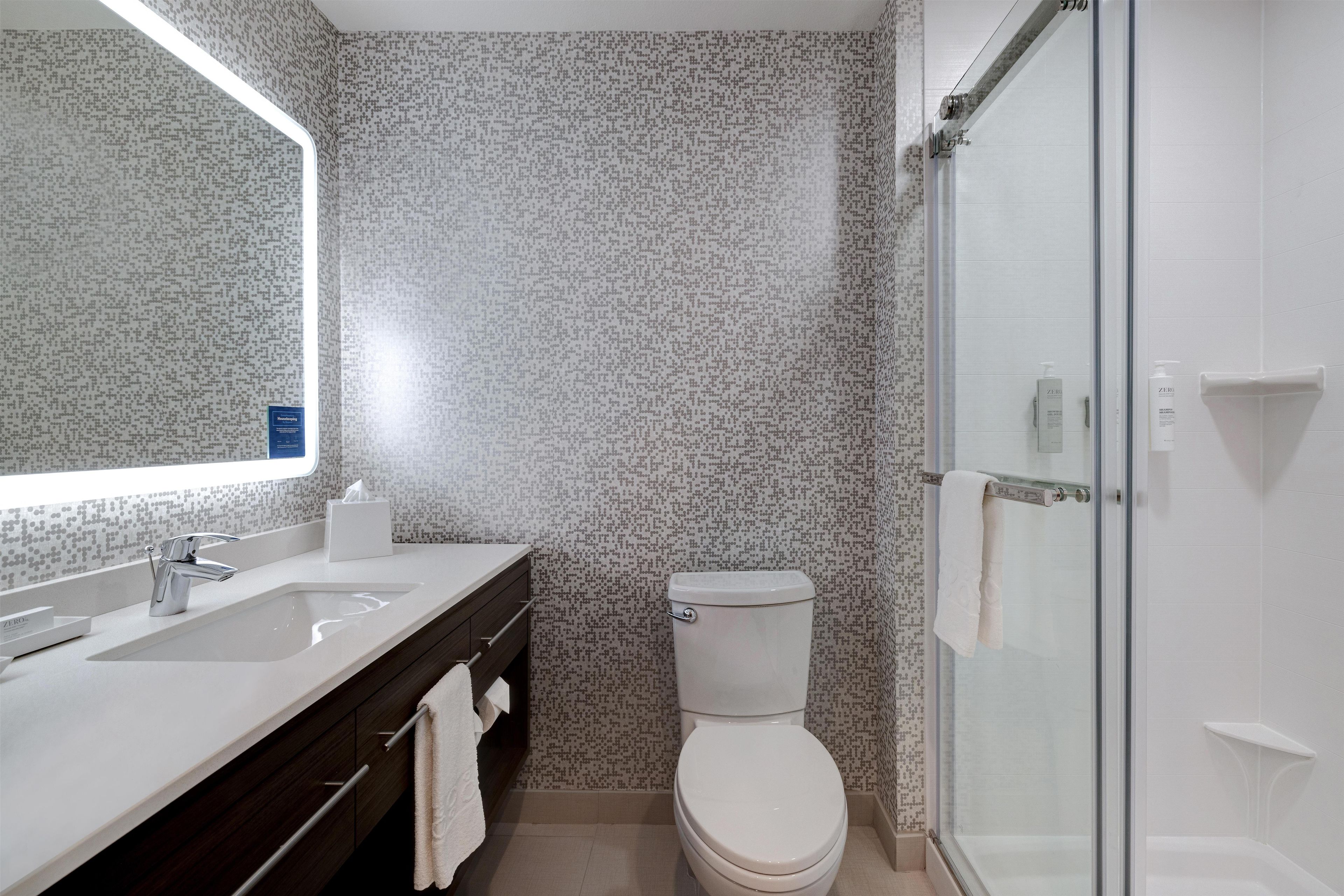 Ein Badezimmer mit Toilette, Waschbecken, Spiegel und Dusche.