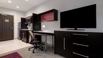Een moderne kantoorruimte met een bureau, stoel, computer en een flatscreen televisie.