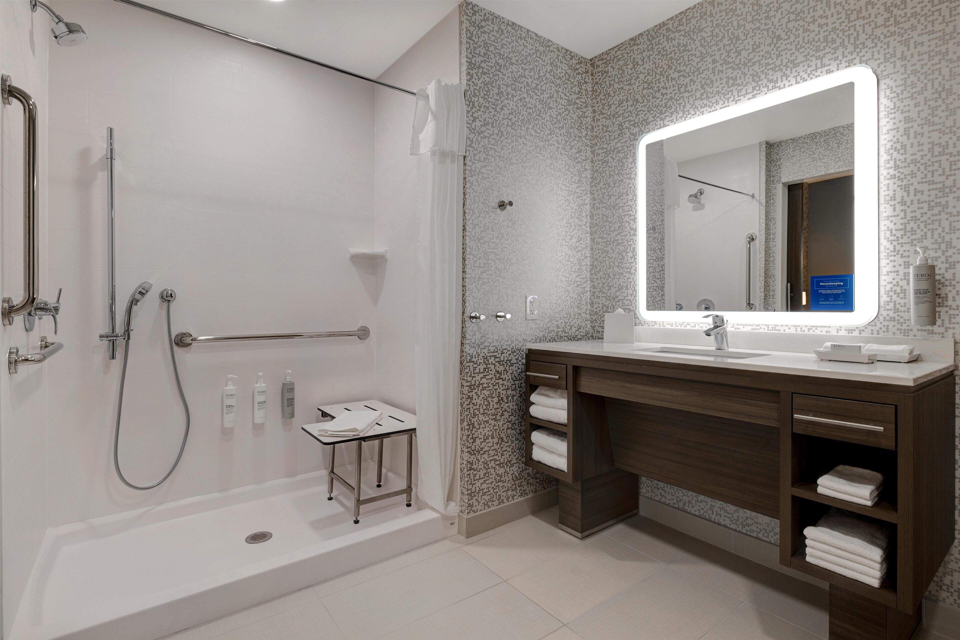 Un baño moderno con ducha, tocador con espejo e inodoro.