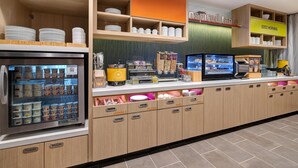 A breakfast bar with a refrigerated display, labeled sections for utensils, plates, mugs, and bowls, and a sign that says 'Good Morning.' - Home2 Suites By Hilton Redding (Redding)