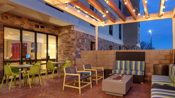 An outdoor patio area with stone walls, wooden beams, and string lights. - Home2 Suites By Hilton Redding (Redding)