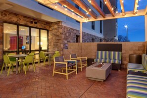 An outdoor patio area with stone walls, wooden beams, and string lights. - Home2 Suites By Hilton Redding (Redding)