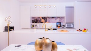 Une cuisine moderne avec des armoires blanches, un robinet doré et un four à micro-ondes.