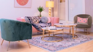 Un salon moderne avec un canapé rose, un fauteuil vert et une table basse ronde.