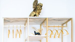 Une étagère blanche agrémentée de détails dorés, sur laquelle sont posés une horloge, des vases et une petite statue.