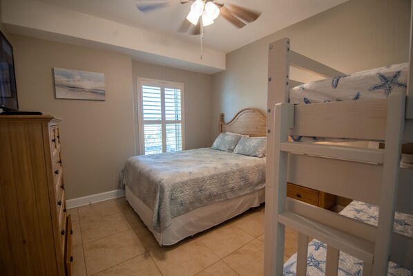 A bedroom with a bed, a ceiling fan, a window, and a bunk bed. - Guest Favorite 10/10! 2BR 2BA, Clean! Gorgeous Sunsets! Beach Service Included! (Panama City Beach)