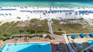 An aerial view of a beach resort with a swimming pool, sun loungers, and umbrellas.